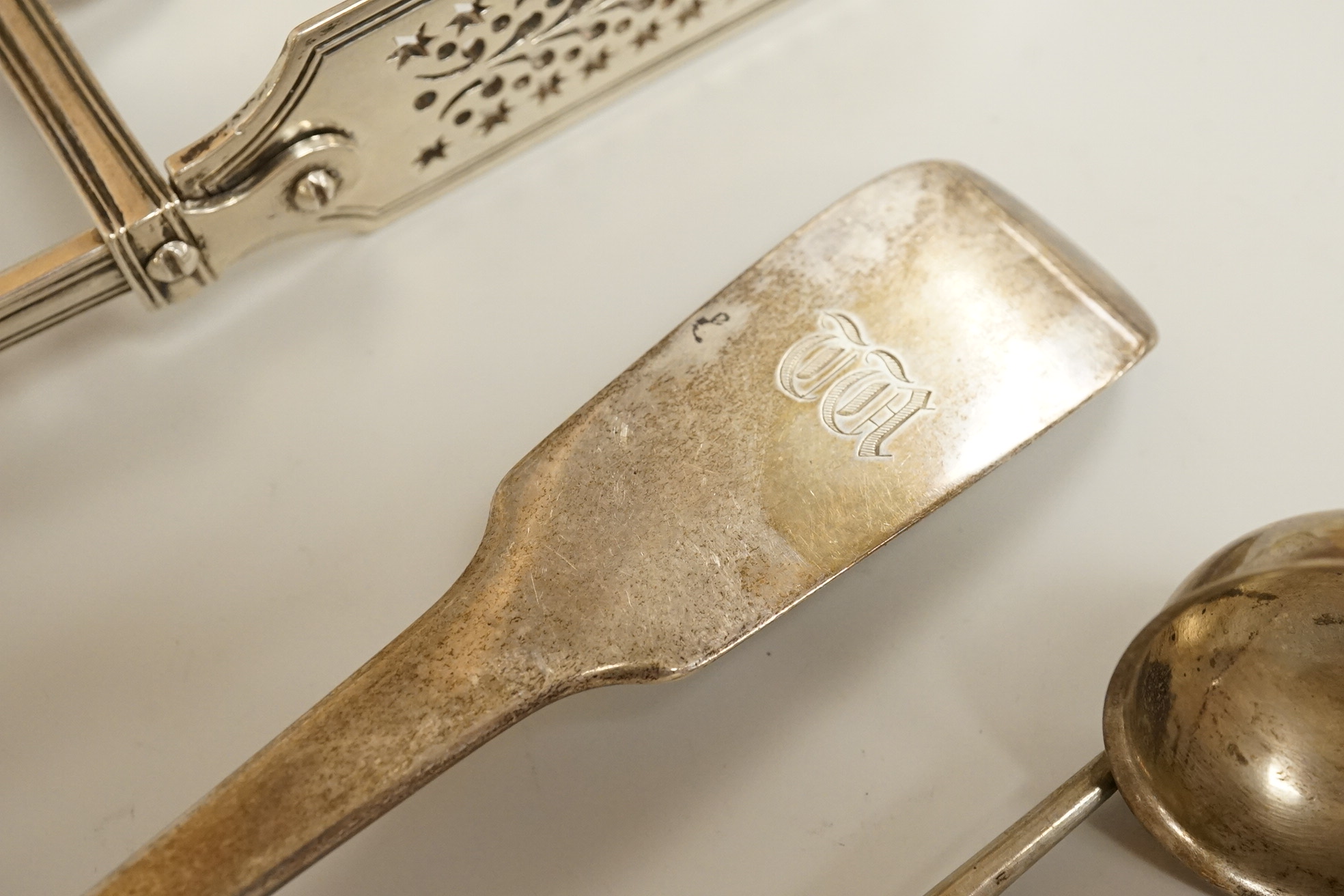 A pair of William IV silver fiddle, thread and shall pattern asparagus servers, a George IV silver fiddle pattern basting spoon, Robert Gainsford, Sheffield, 1826, 31.2cm, 10.8oz and two 19th century white metal toddy la